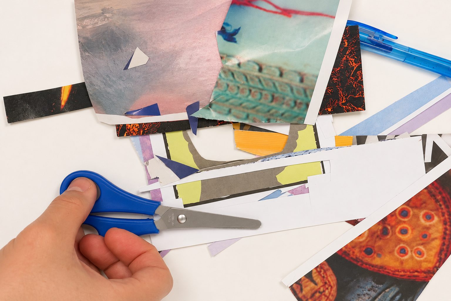 Hands arranging a collage of colourful patterned papers, scissors in hand