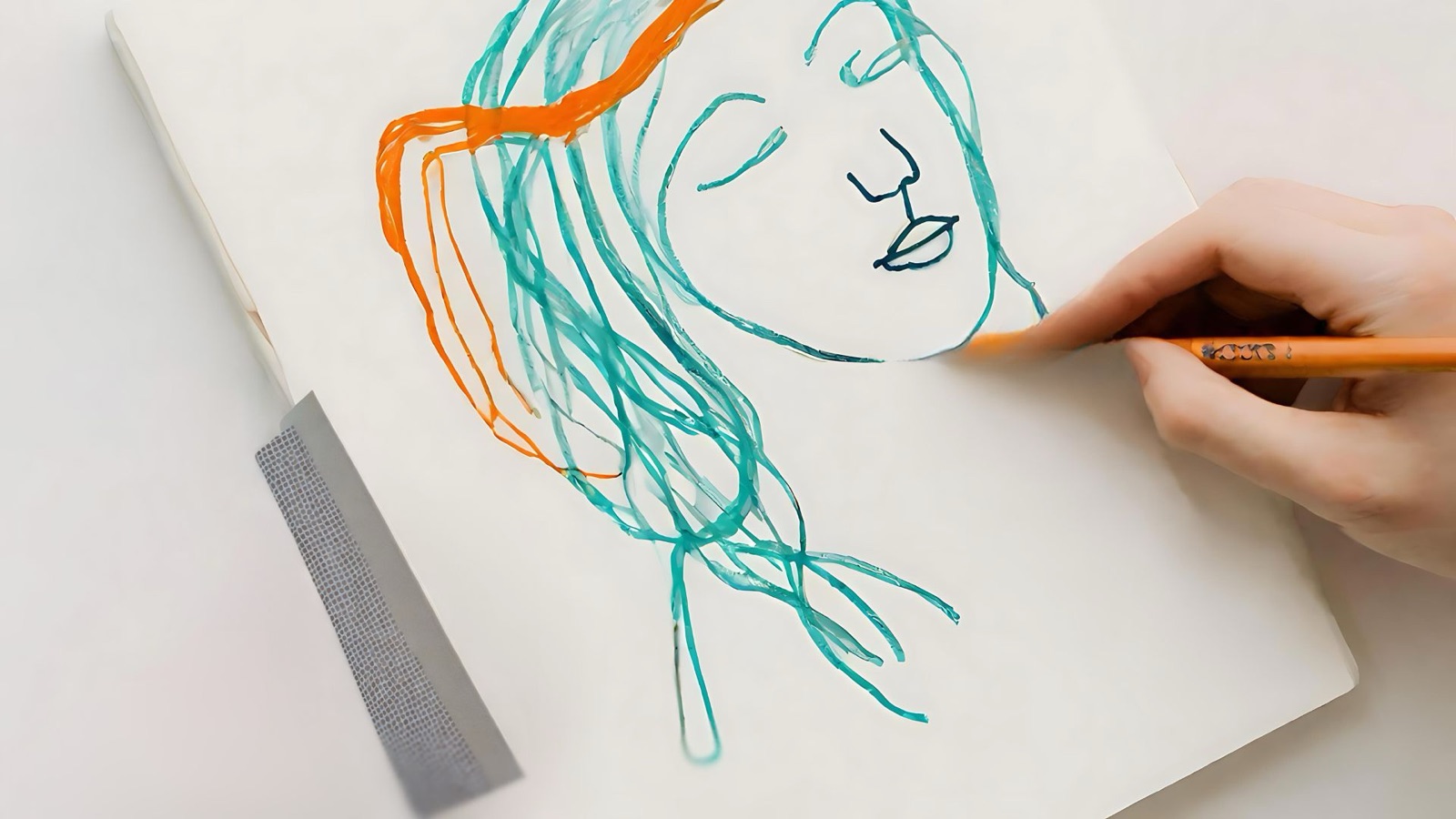 A hand drawing a face in teal and orange line work
